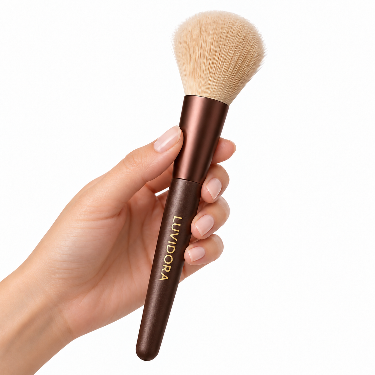 LUVIDORA powder brush held in a hand on a white background